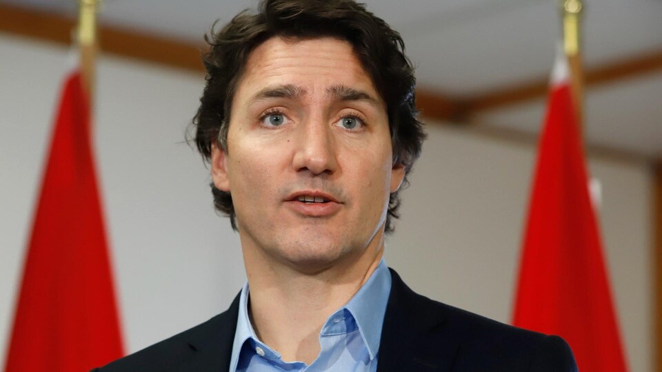 Le premier ministre du Canada Justin Trudeau, devant des drapeaux canadiens.