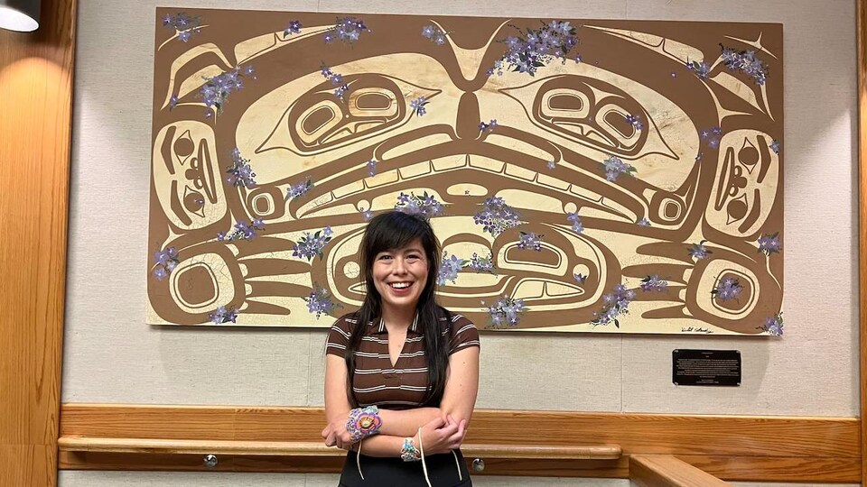 Une femme souriante pose devant une oeuvre d'art.