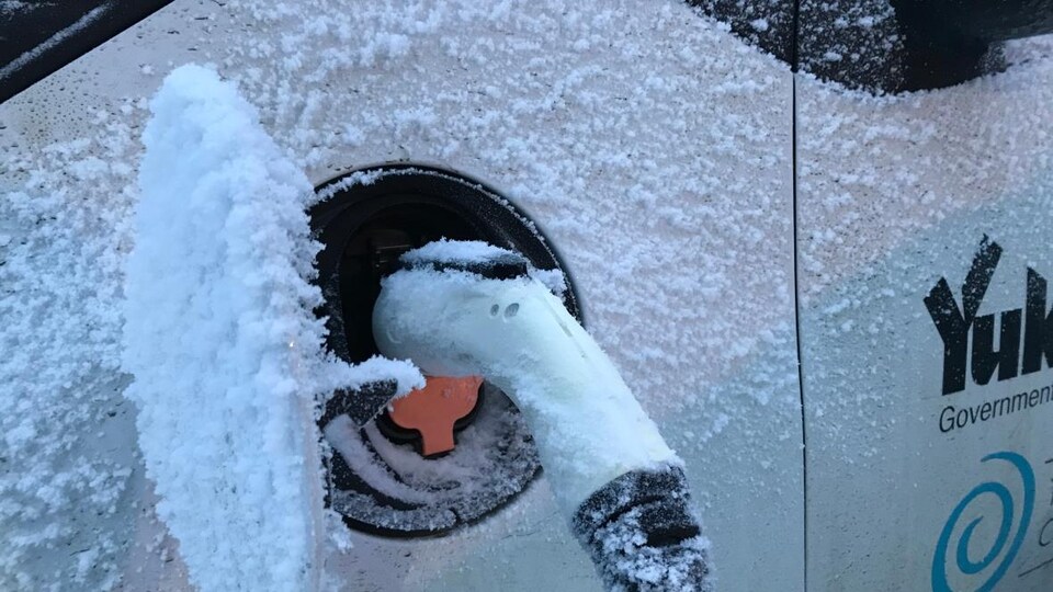 Une voiture électrique en recharge en hiver.