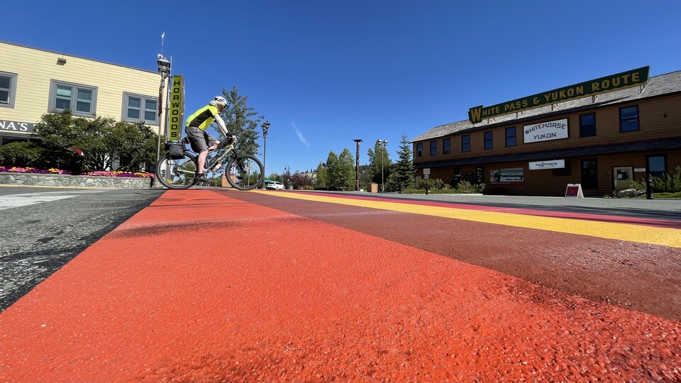 Un vélo traversant les couleurs d'un passage piéton.