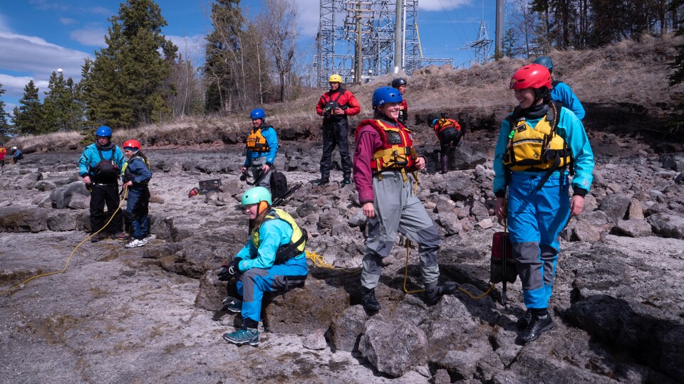 Des participants avec leur casque et leur veste de sauvetage sur la berge du fleuve Yukon, à Whitehorse, le 10 mai 2023. 