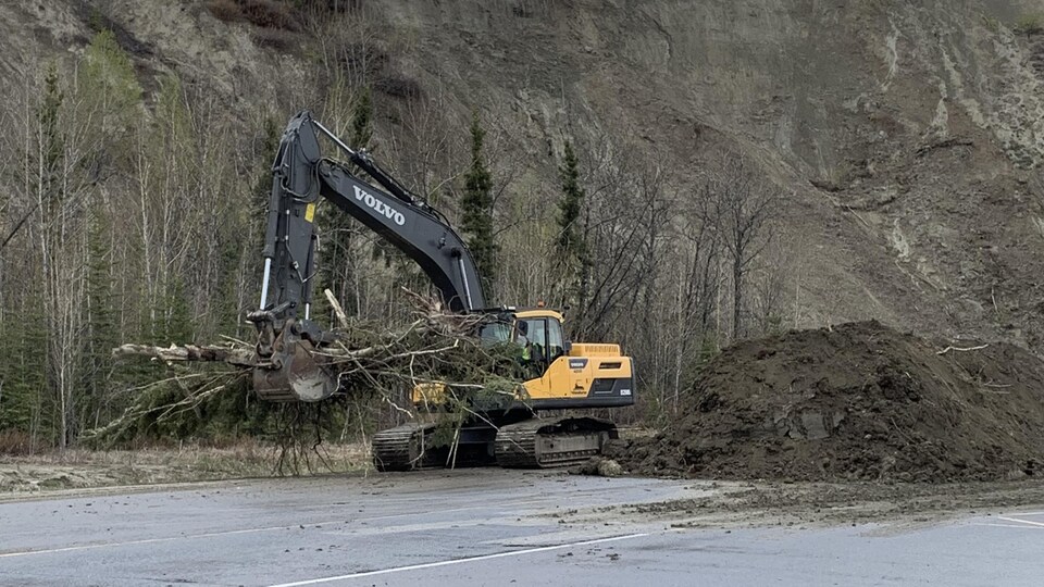 A mechanical shovel delivers debris next to a pile of dirt.