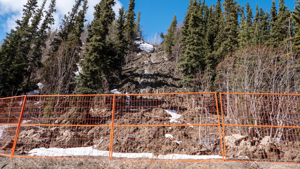 Des barrières oranges sont installées au pied d'une coulée de boue.