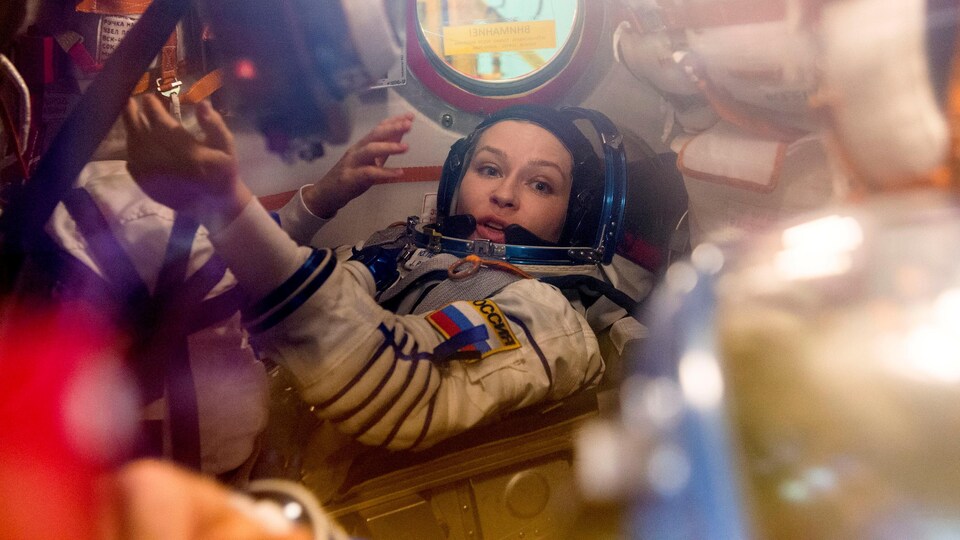 Une femme portant un costume d'astronaute s'entraîne en apesanteur dans un module. 