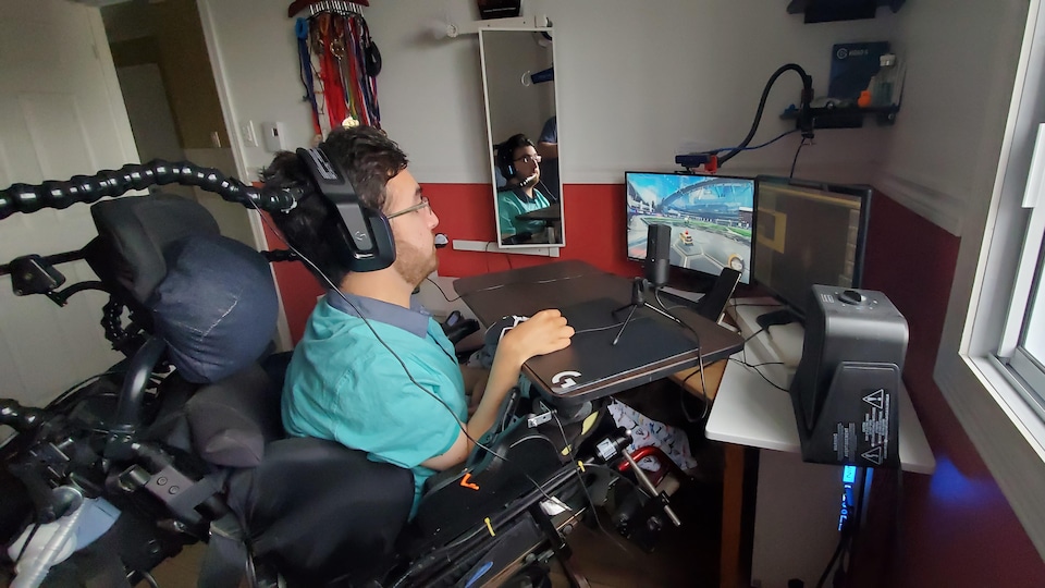 Un homme en fauteuil roulant joue au jeu vidéo «Rocket League» sur un ordinateur.