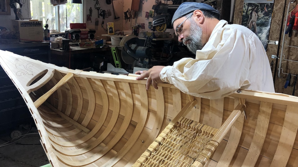 Yvan Tanguay sable un canot dans un atelier.