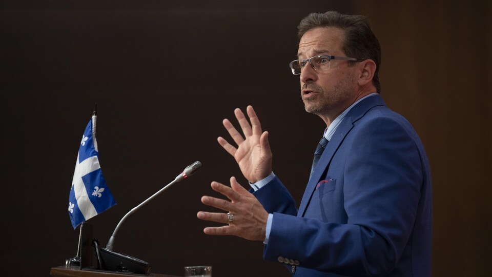 Yves-Francois Blanchet parle au micro, les mains levées devant lui.