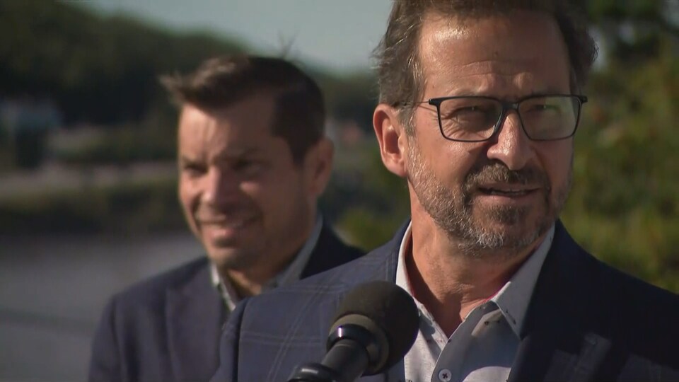 Yves-François Blanchet parle au micro tandis que se tient derrière lui Guy Bernatchez.