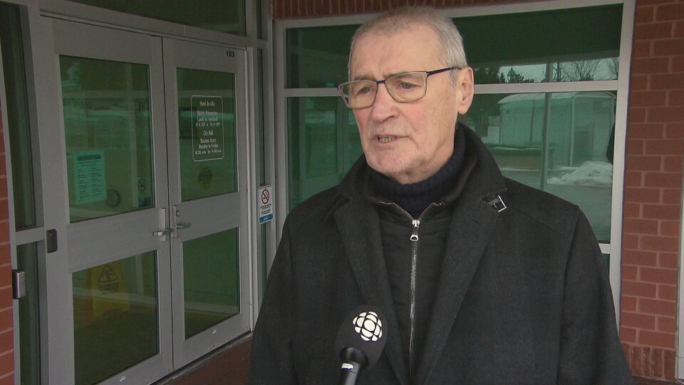 Yvon Lapierre devant un micro de Radio-Canada, à l'extérieur devant un bâtiment.