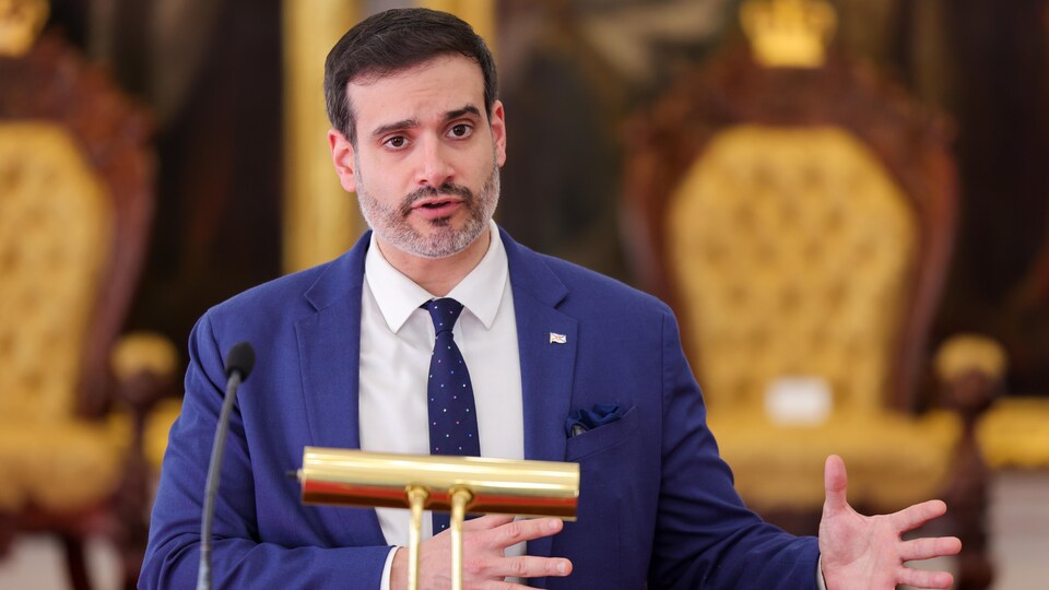 Devant un lutrin et une petite lampe dorée, Zach Churchill parle aux médias dans l'édifice de la législature à Halifax.