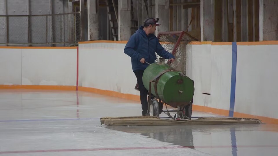 Une personne pousse une surfaceuse ancienne sur la glace de la patinoire de Lang, en Saskatchewan.