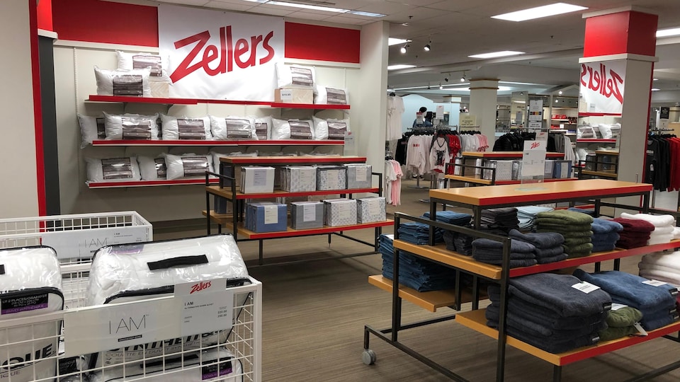 Une section de magasin avec des draps, des serviettes et une affiche Zellers.