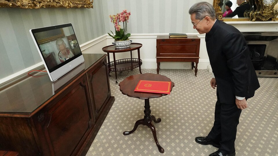 Zheng Zeguang s'incline devant la reine, visible sur un écran d'ordinateur.