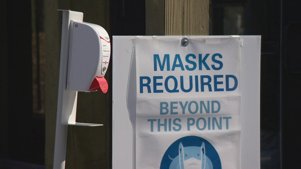 Une station de désinfectant et une affiche qui rappelle le port du masque. 