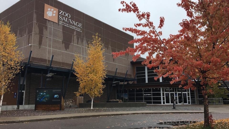 Le bâtiment en pierre et en bois affiche le logo du zoo.