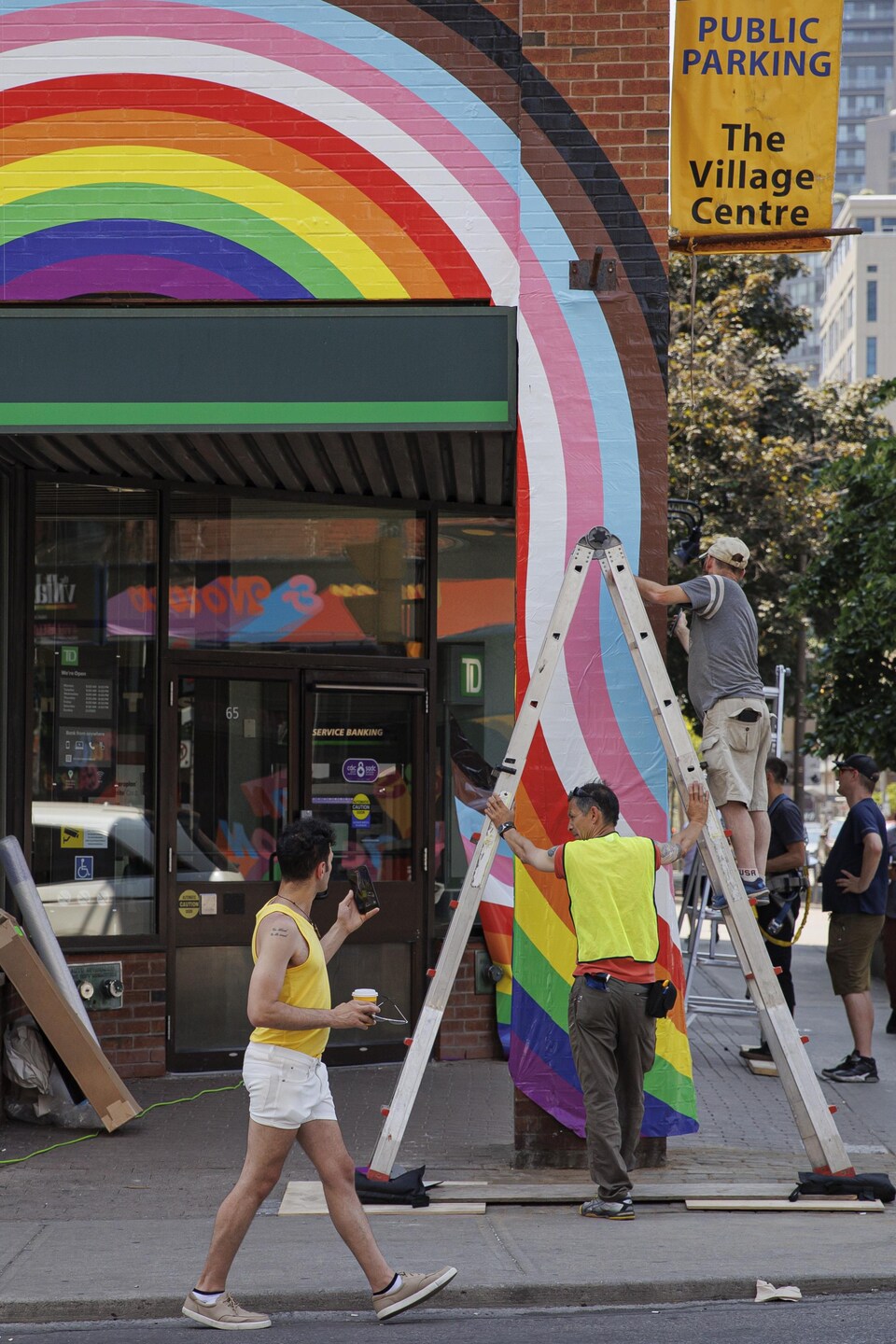 Des travailleurs installent une bannière arc-en-ciel à l'occasion du Mois de la Fierté dans le village gai de Toronto, sur la rue Church.