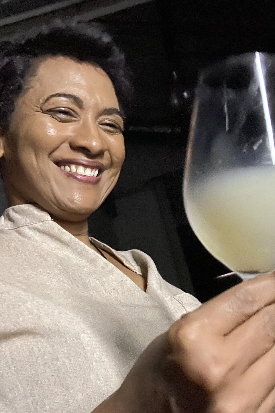 Carmen Stevens tient une coupe dans laquelle il y a un liquide jaune et opaque. 