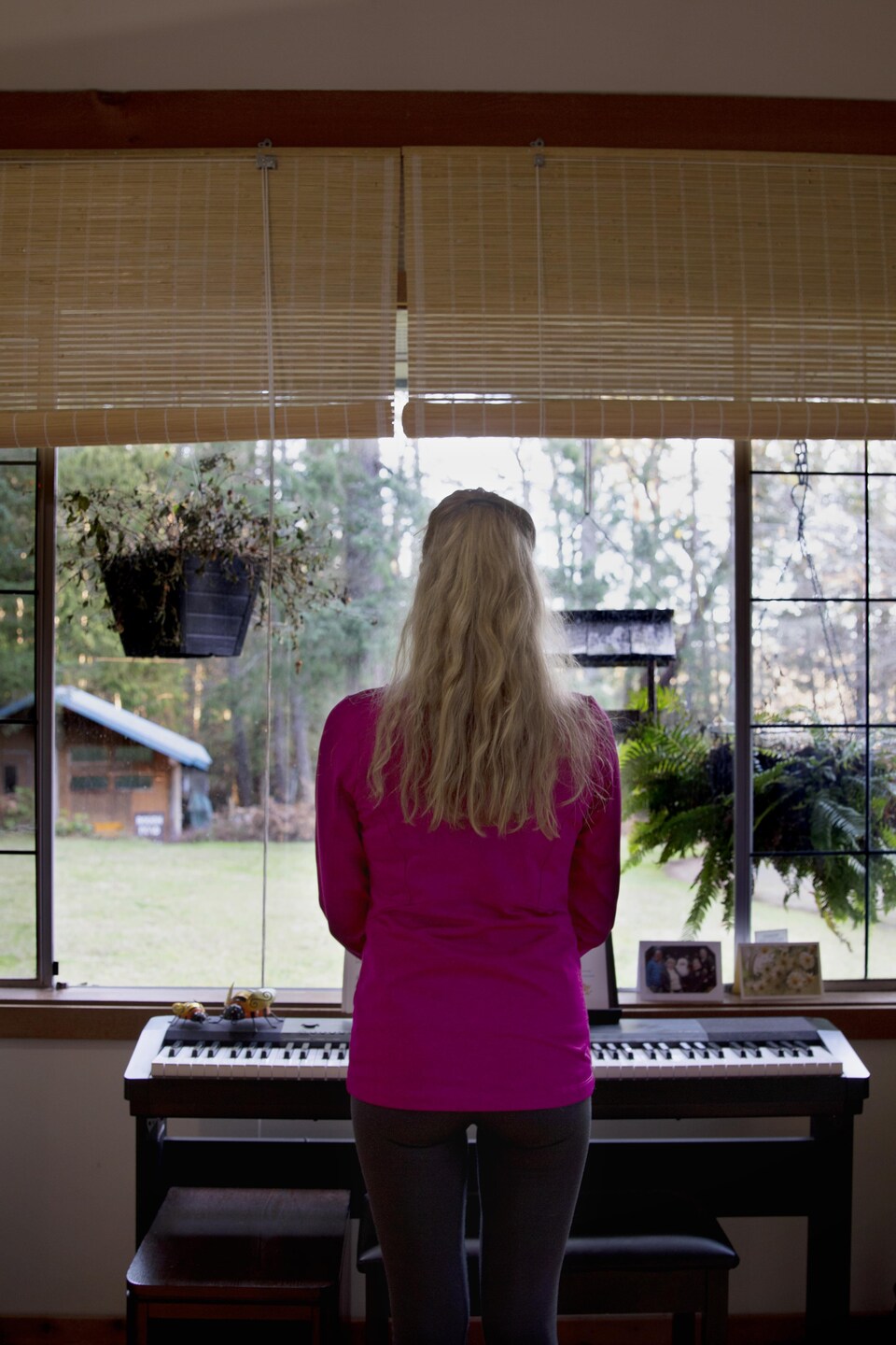 Une femme devant un piano regarde par la fenêtre
