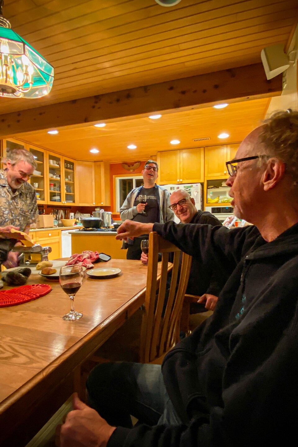 Buff Allen prépare des pâtes pendant que les musiciens sont assis autour d'une table discutant et souriant.