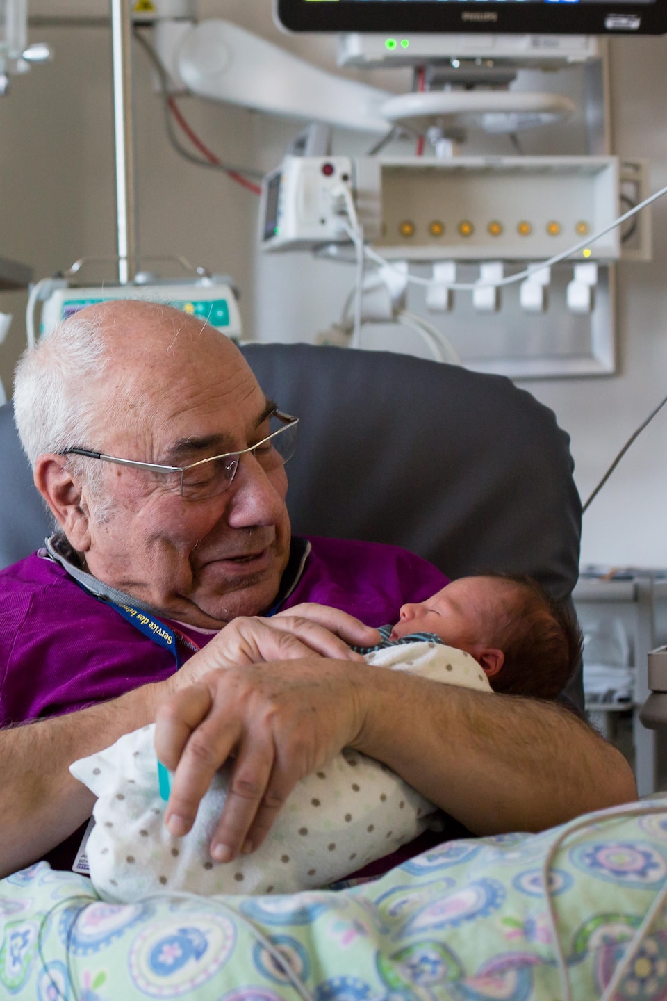 Joseph Kerba regarde tendrement un bébé prématuré qui dort dans ses bras.