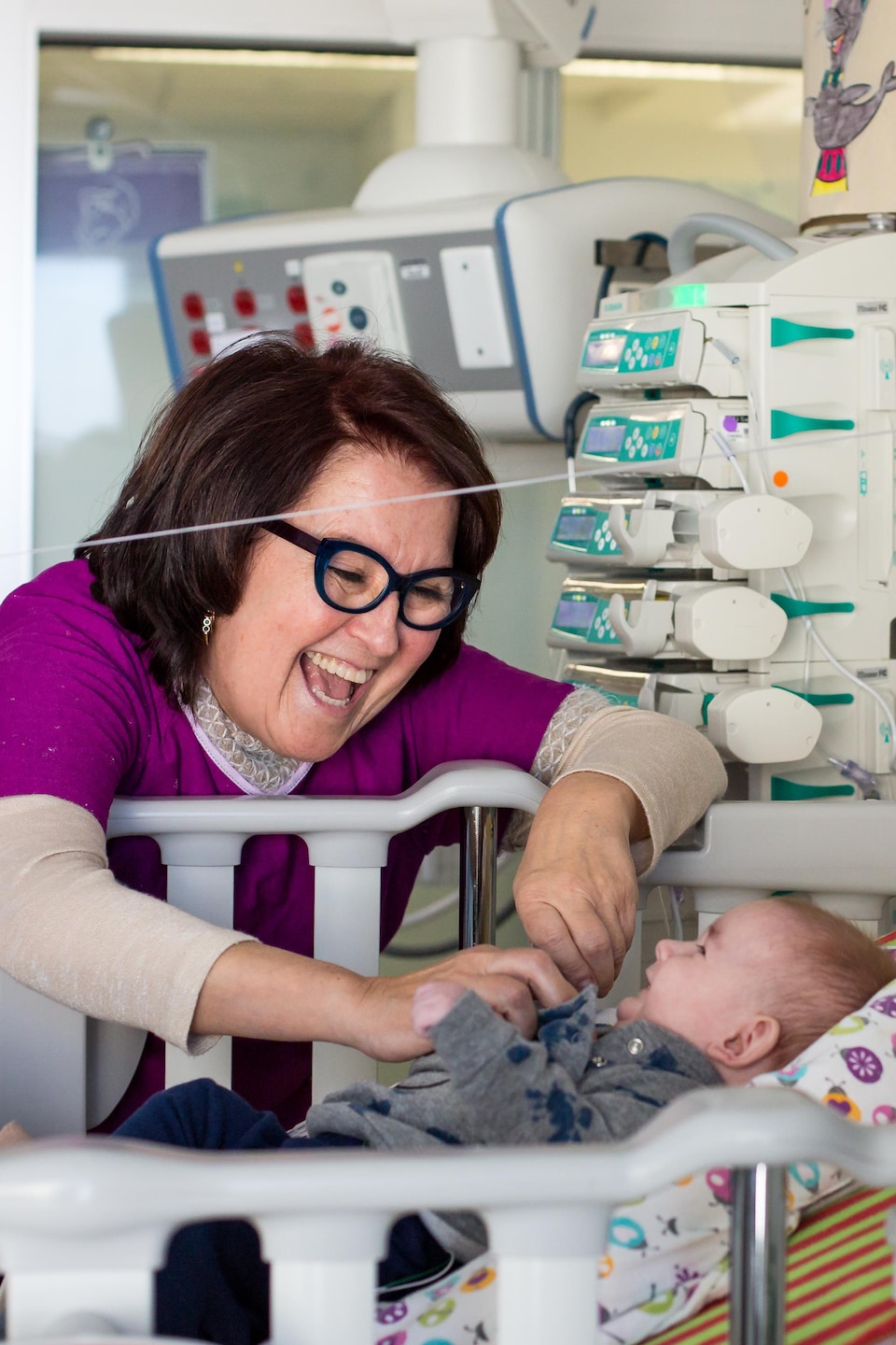 La bénévole Louise Lafond arbore un large sourire en chatouillant un bébé prématuré.