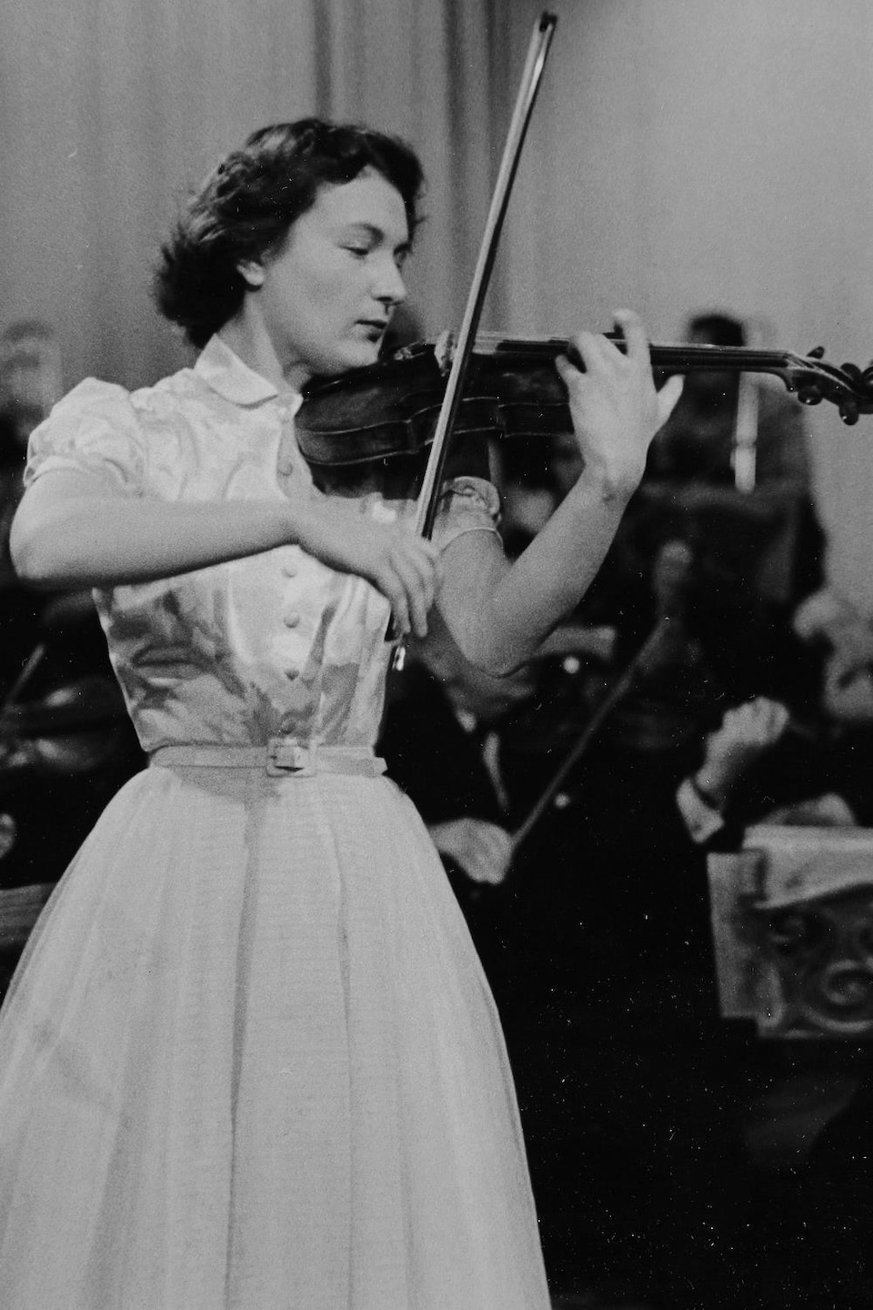 Blanche Tarjus jouant du violon devant un orchestre.