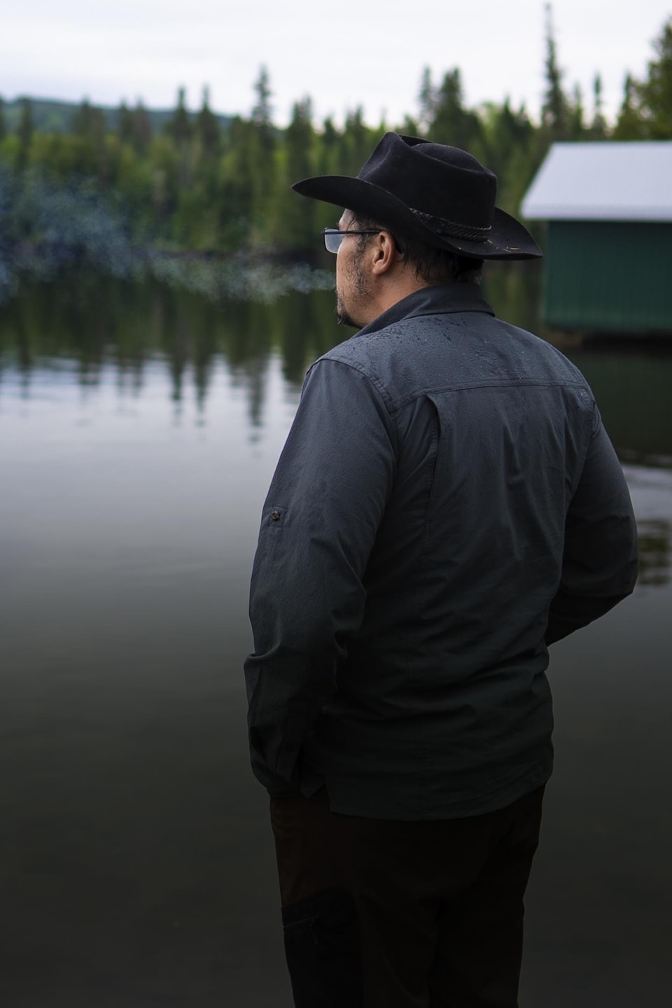 Un homme fume devant un lac.
