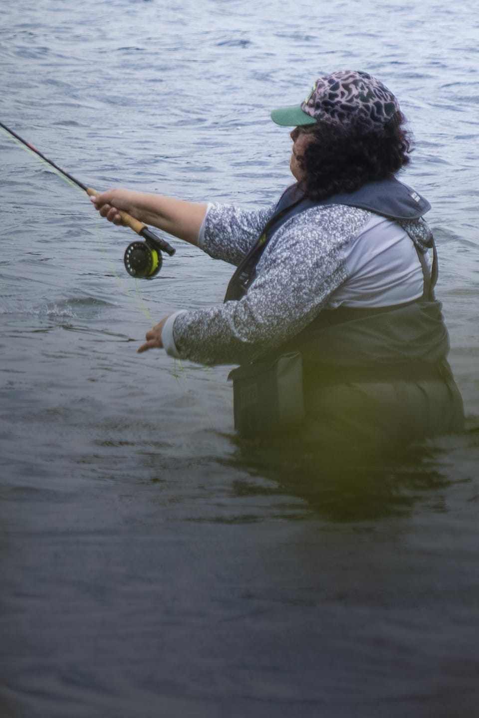 Une femme pêche à la mouche dans un lac.