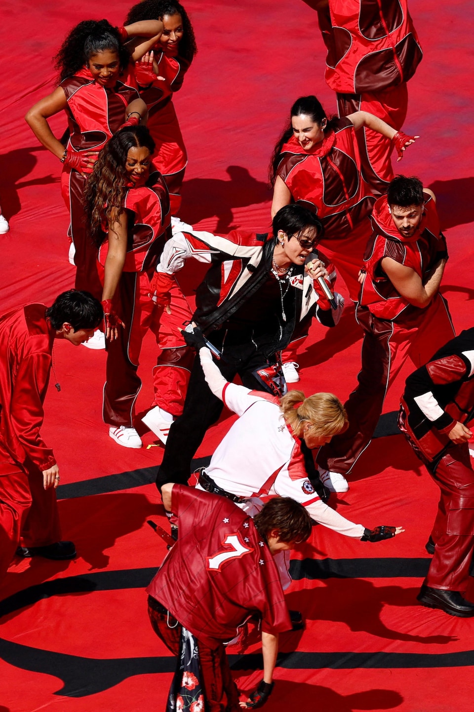 Des gens vêtus de rouge dansent autour d'un chanteur.