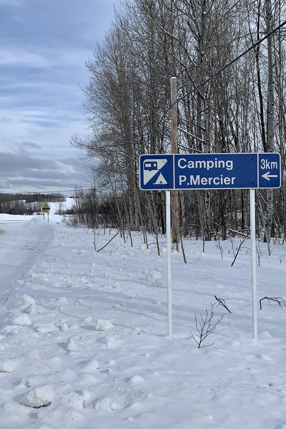 Une pancarte près d'un chemin indique que le Camping Mercier est à trois kilomètres.
