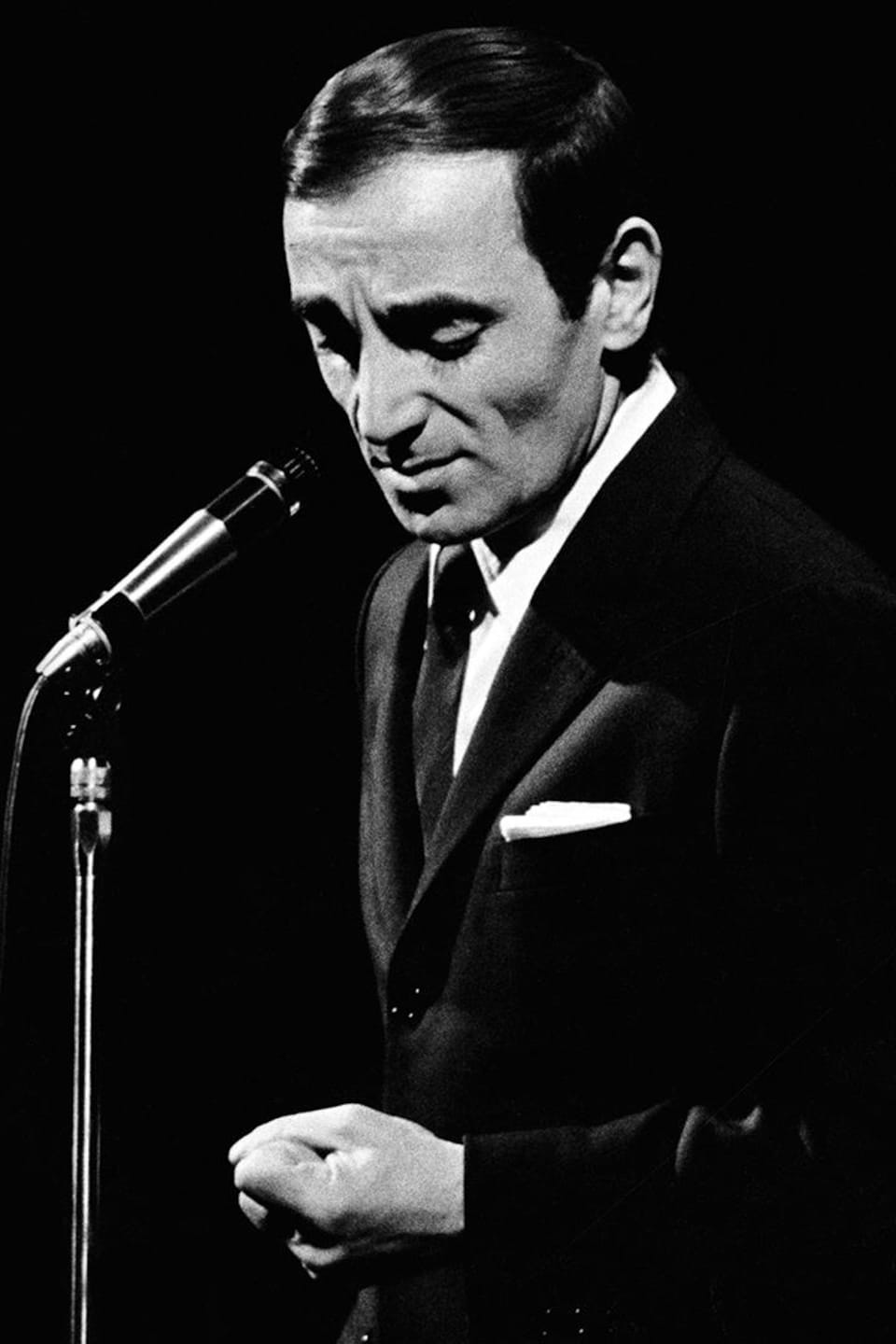 Charles Aznavour derrière un micro sur pied.