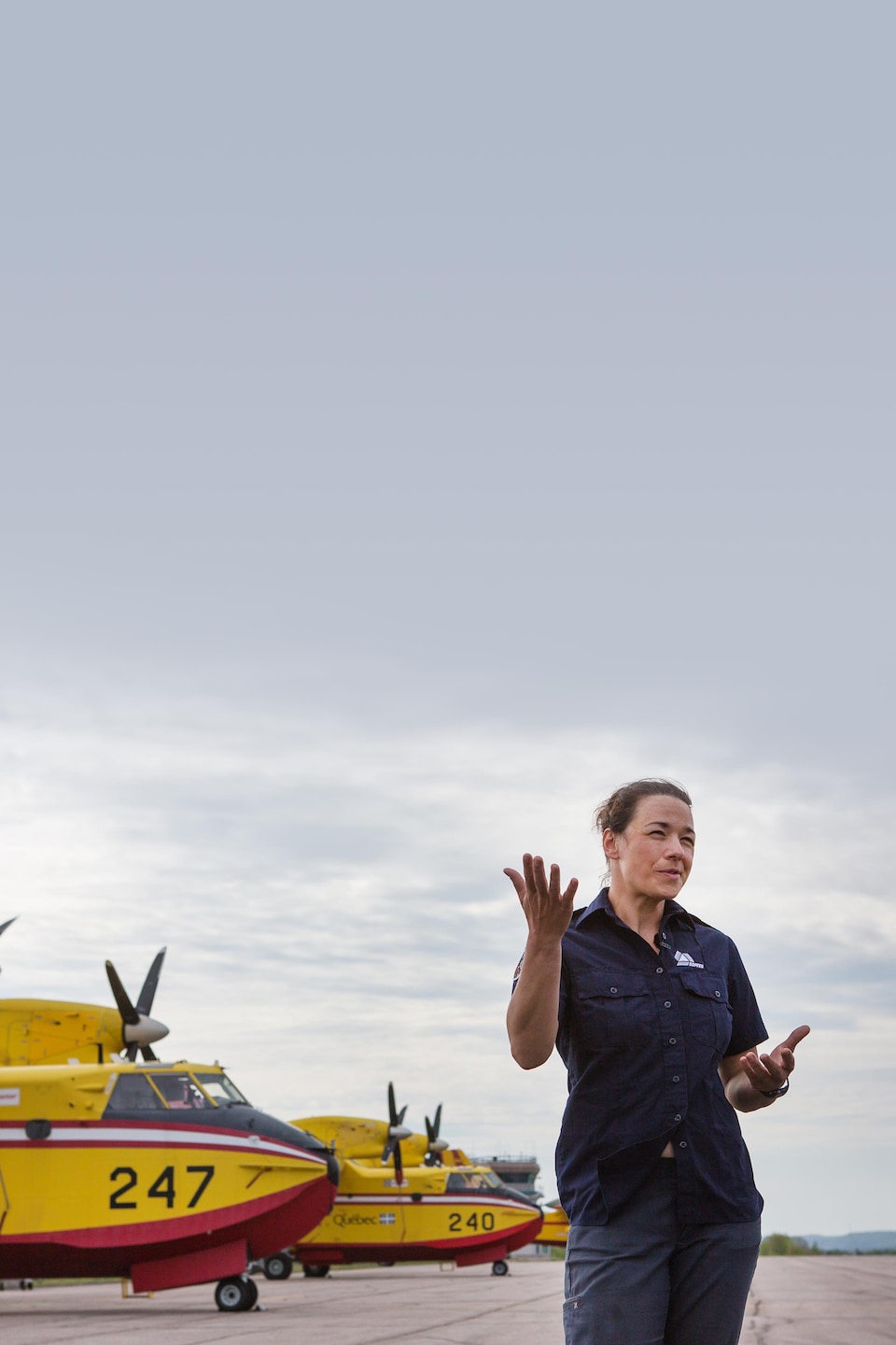 Claudia Sheehy est devant des avions-citernes et parle.