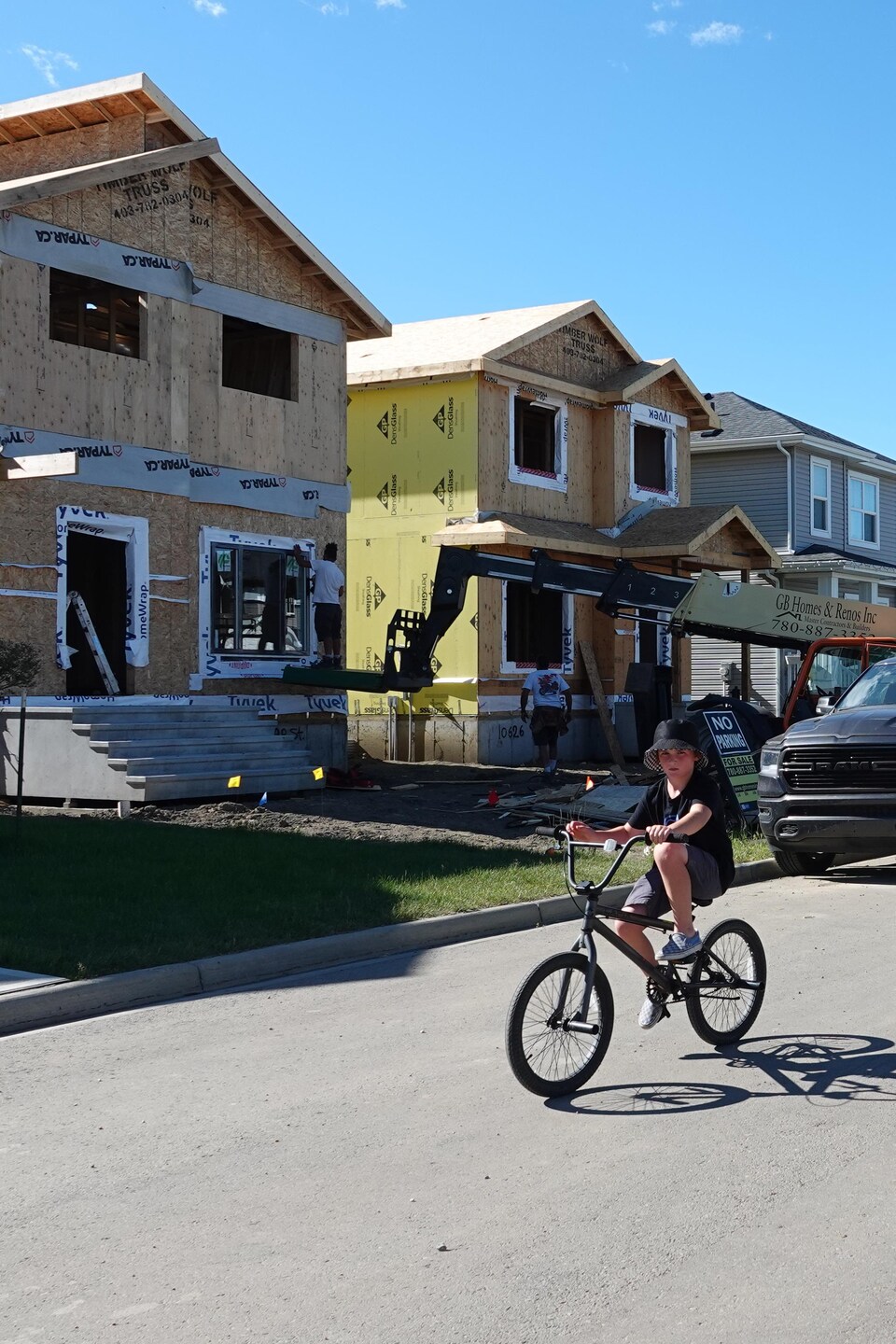 Un enfant à bicyclette dans une rue bordée de maisons en construction.