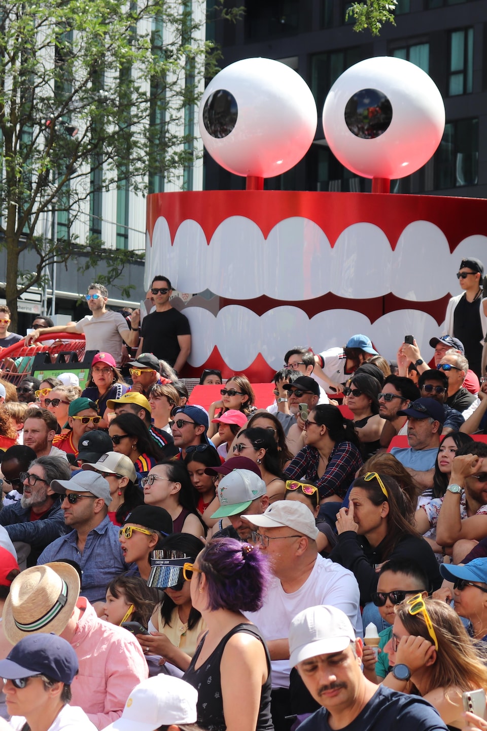 Des partisans attendent le début du match, devant un dentier géant qui sert de décoration au festival Juste pour rire.
