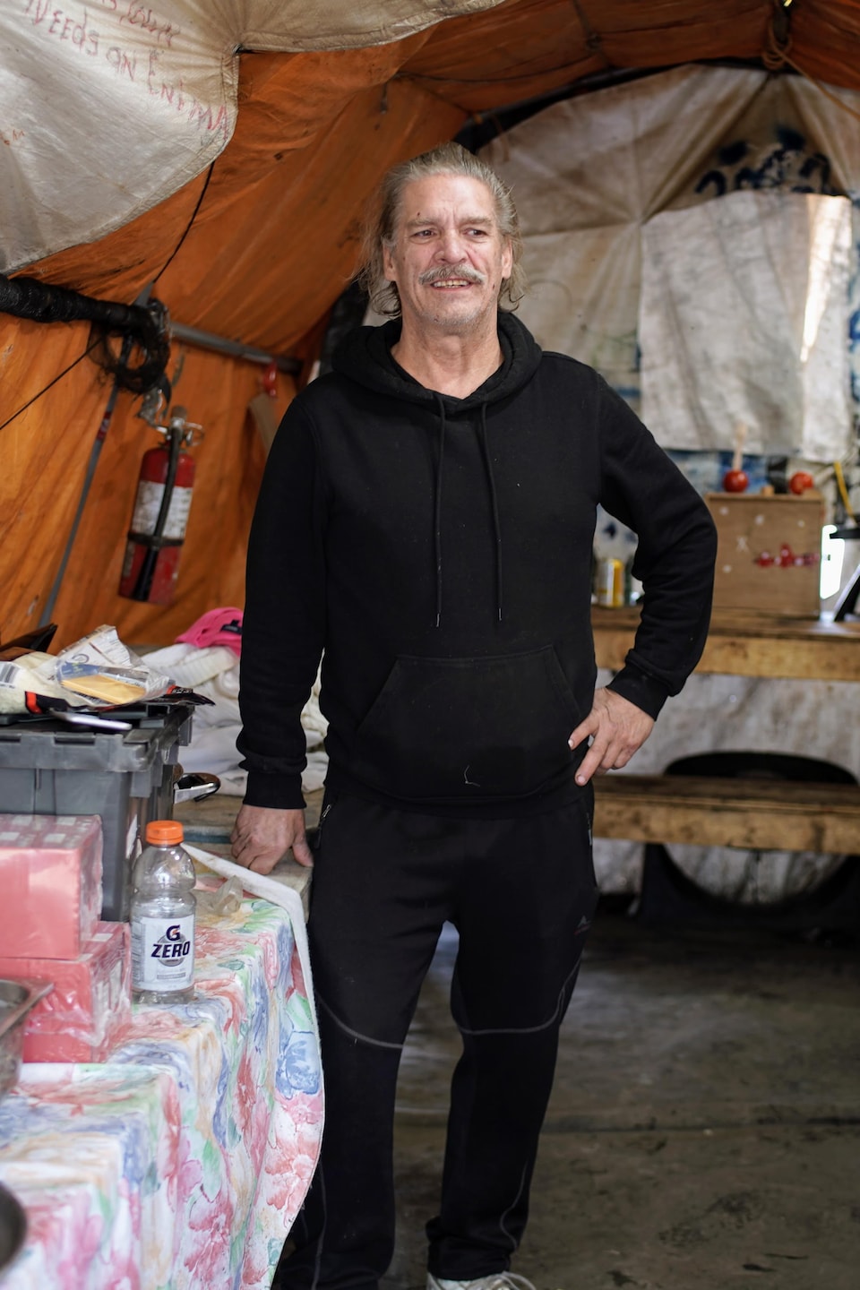Dave est en train de cuisiner, dans une cuisine aménagée sous une tente, au parc Crab, à Vancouver, fin octobre 2023. 