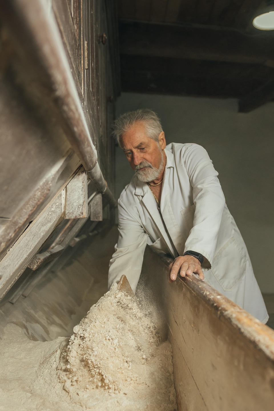 Jean-Guy Tremblay inspecte la farine dans une cuve de bois.