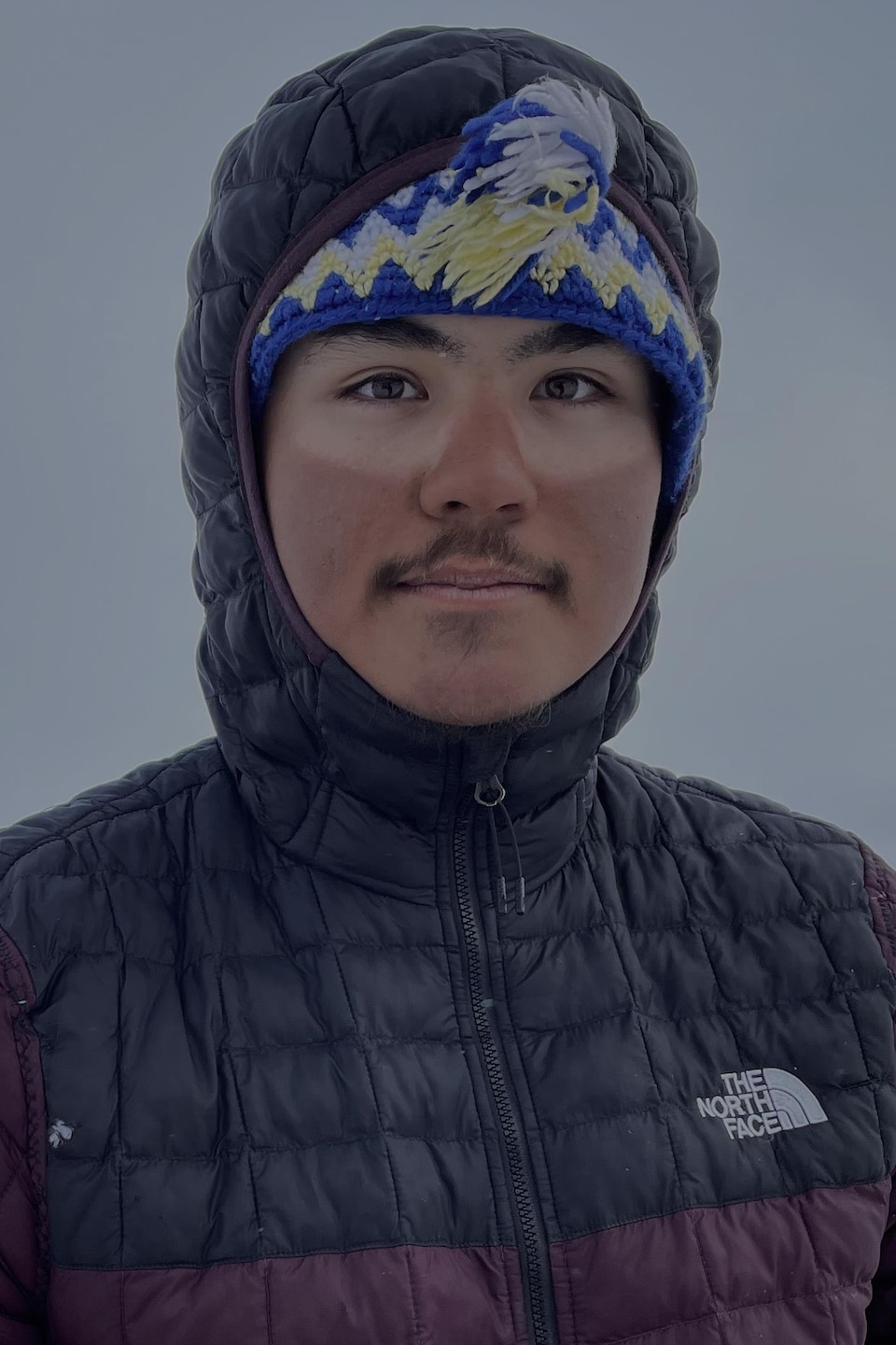 Portrait de Devon Manik, une veste zippée jusqu'au coup, avec un bonnet et une capuche, au mois de juin à Resolute Bay, dans le nord du Nunavut.