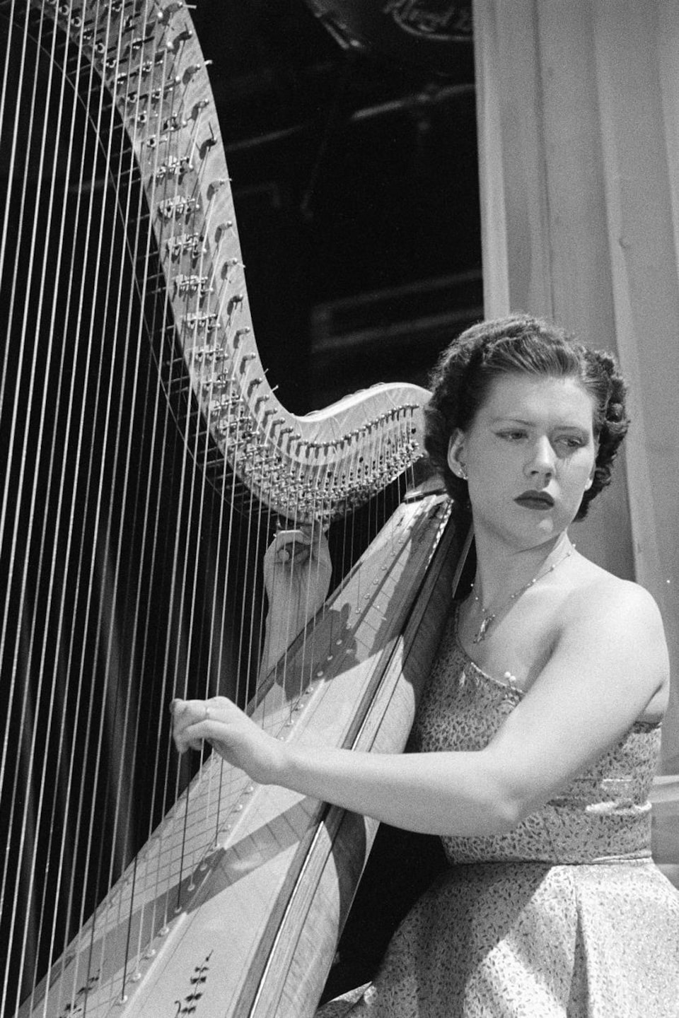 Dorothy Weldon jouant de la harpe, le regard tourné vers le sol.