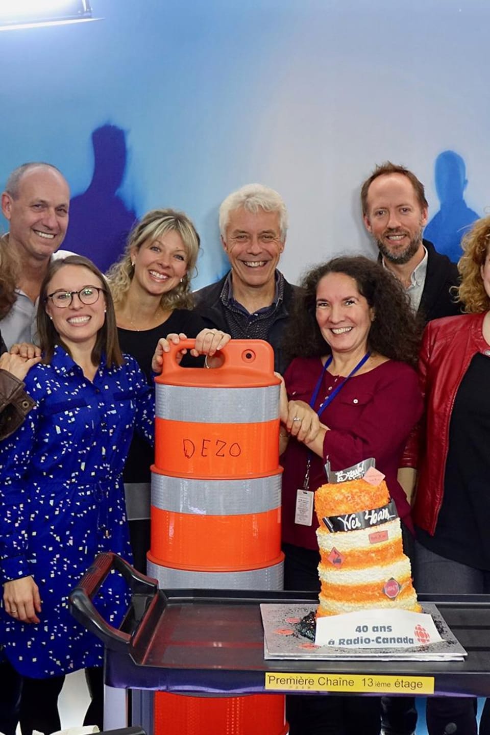 L'équipe de l'émission Gravel le matin prend la pose derrière un gâteau en forme de cône de la voirie pour souligner les 40 ans de métier du chroniqueur à la circulation Yves Desautels.