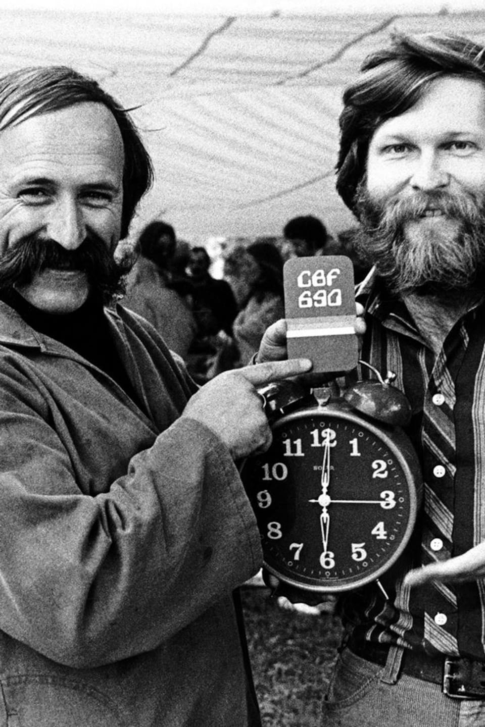 Jacques Houde et Joel Le Bigot tiennent un cadran qui indique six heures.