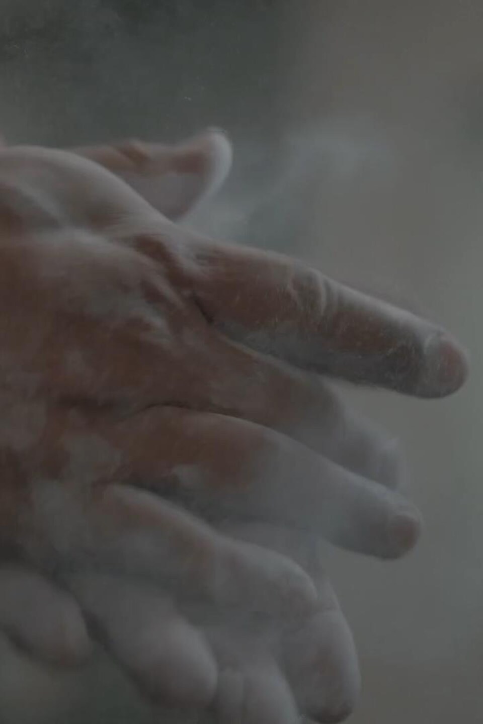 Deux mains en train de se taper l'une contre avec nuage de craie de gymnastique. 