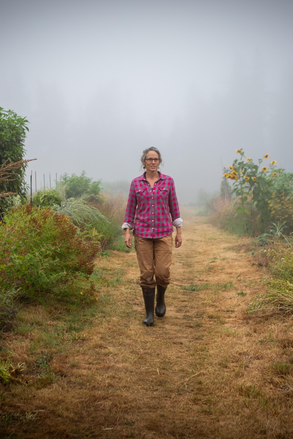 Fiona Hamersley Chambers marche sur un sentier, dans la brume à la ferme Metchosin, dans le sud de l'île de Vancouver, en août 2024.