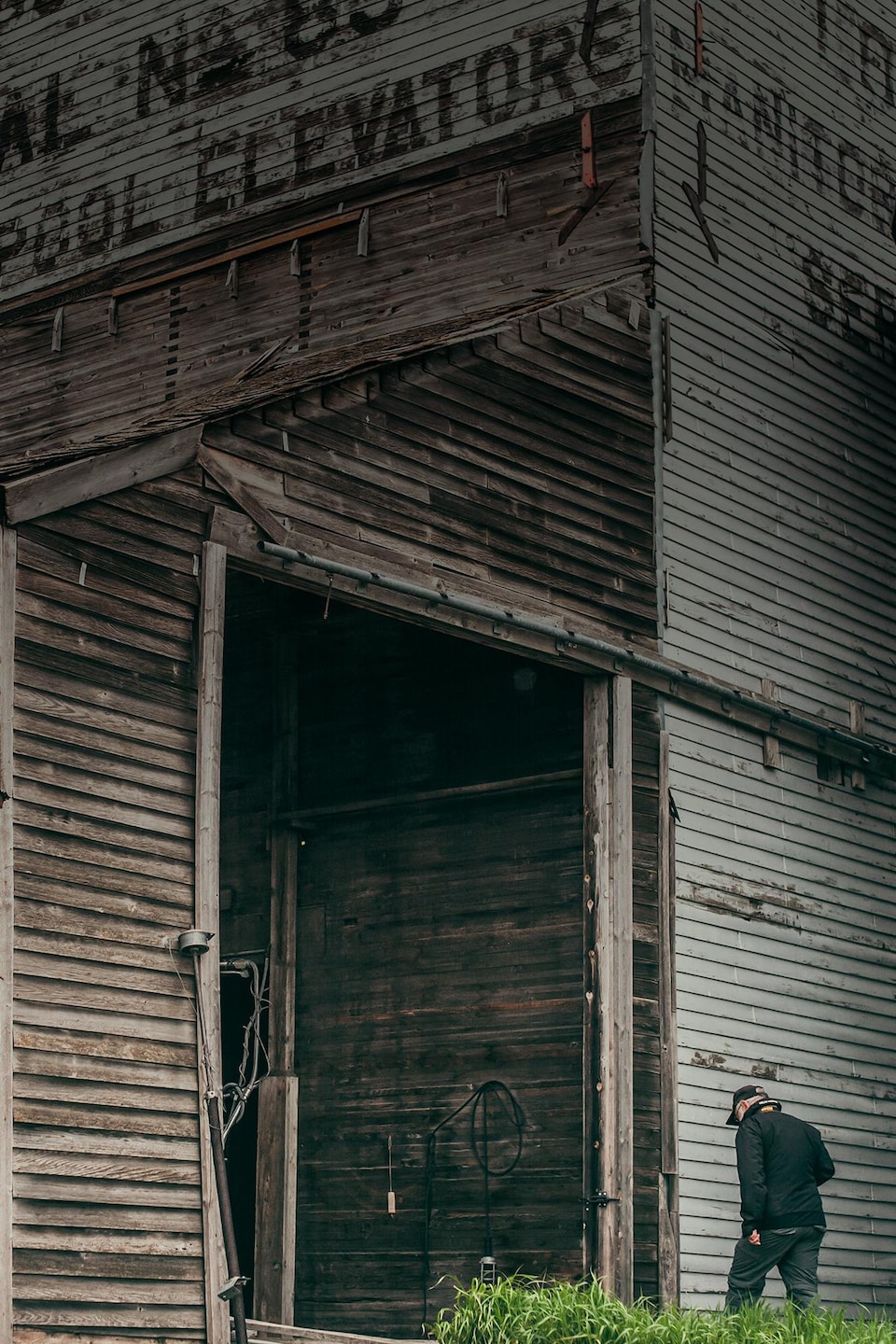 Gordon Goldsborough marche vers un ancien silo à grain tout en bois, à Barnsley au Manitoba, début juin 2022.