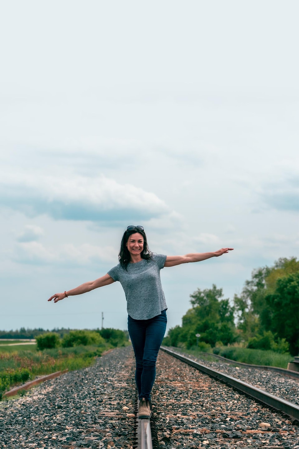 Janelle Fillion marche sur des rails de chemin de fer au milieu de la campagne manitobaine, à Dufrost, début juin 2022. 