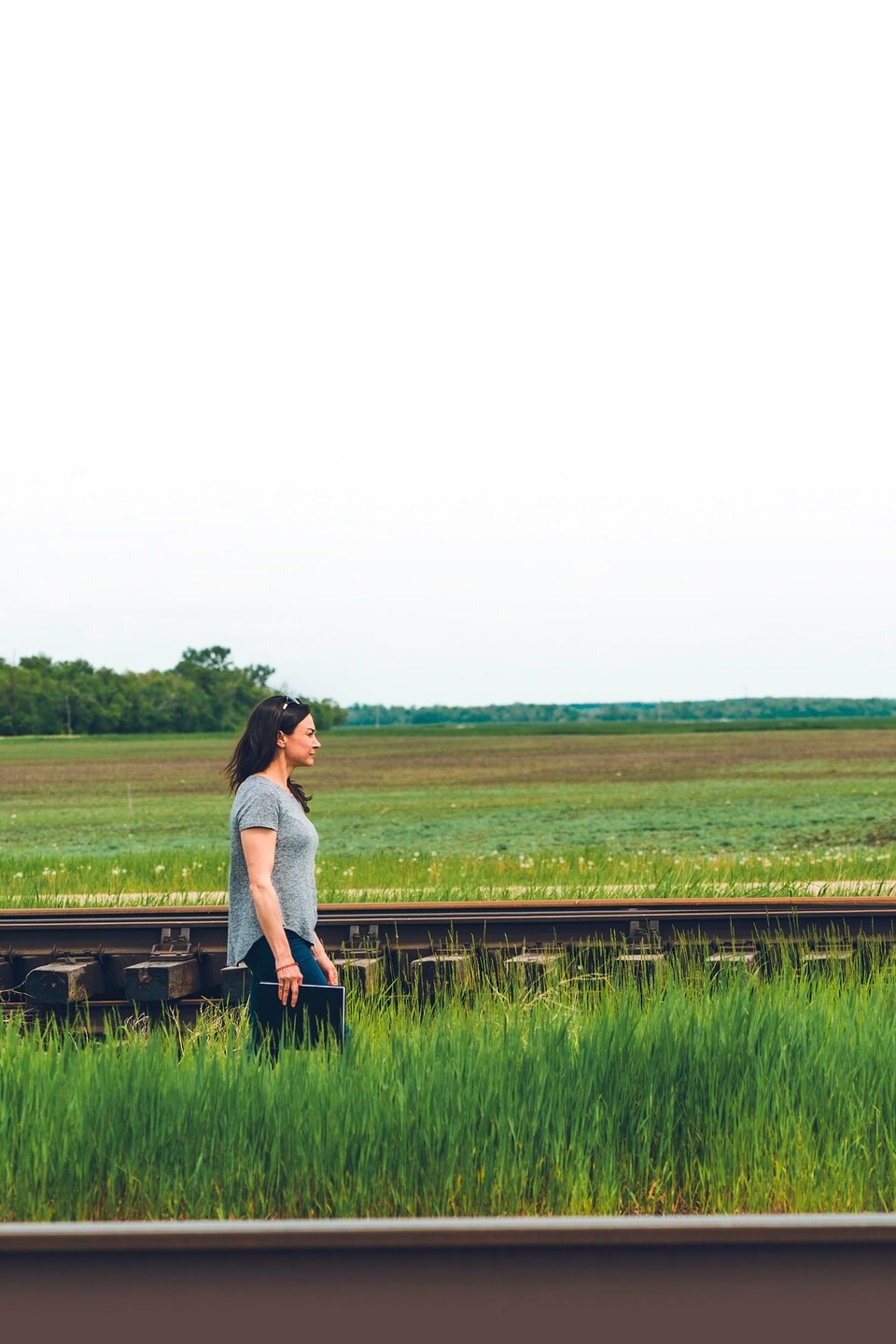 Janelle Fillion marche dans un champ le long de railles qui ne mènent nulle part, à Dufrost, au Manitoba, début juin 2022.