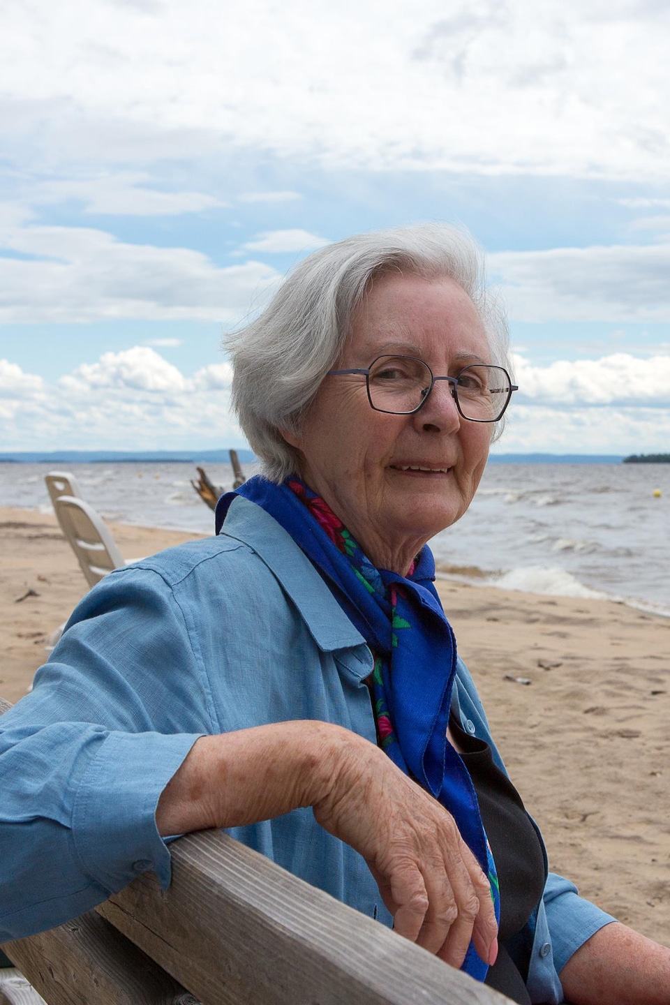 Une femme devant une plage assise sur un banc