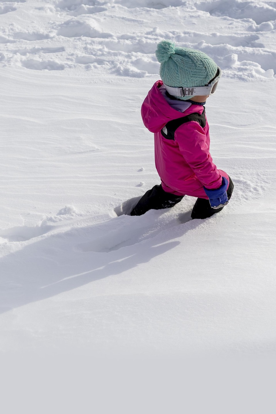 Un enfant marche dans la neige épaisse, laisasnt derrière lui des traces de pas.
