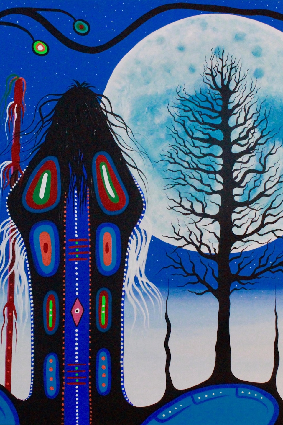 La toile représente une personne de dos qui observe la pleine lune, avec un arbre devant.