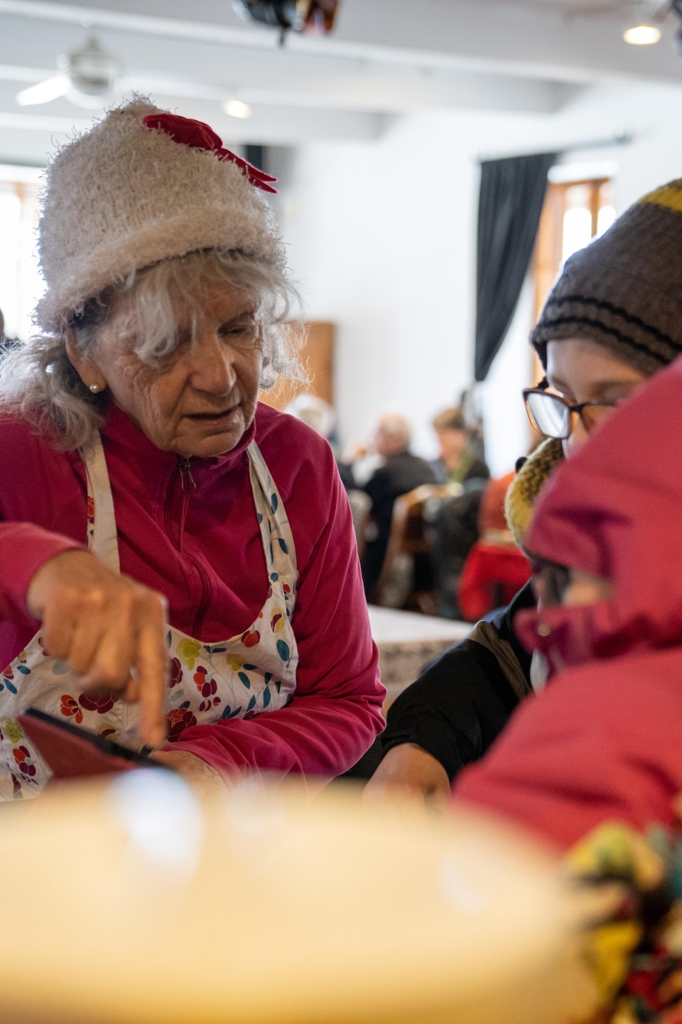 Une dame habillée de rouge sert à dîner à des enfants.