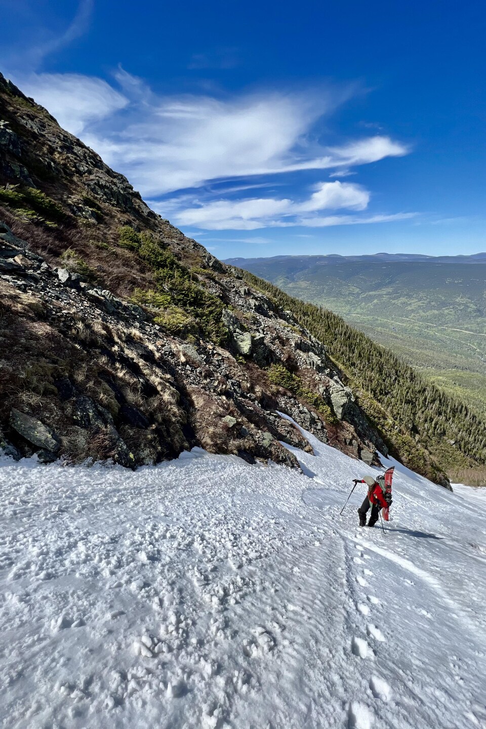 Un skieur fait l'ascension d'une piste enneigée en été.